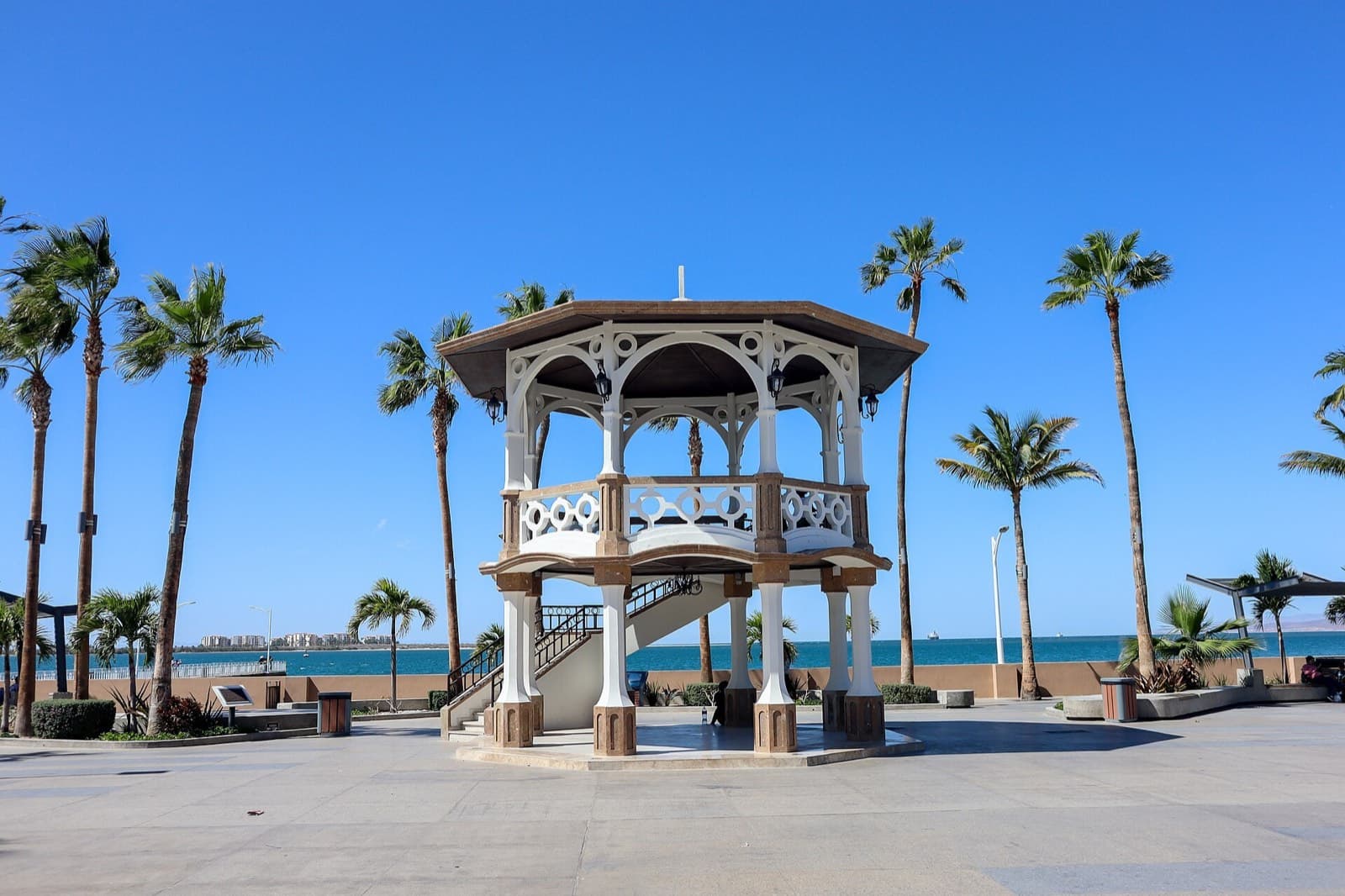 Kiosco blanco del Malecón de La Paz rodeado de palmeras con la bahía al fondo