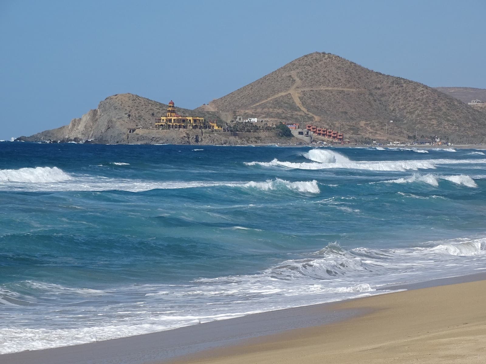 Playa Los Cerritos, cerca de Todos Santos, con oleaje azul y cerro desértico al fondo