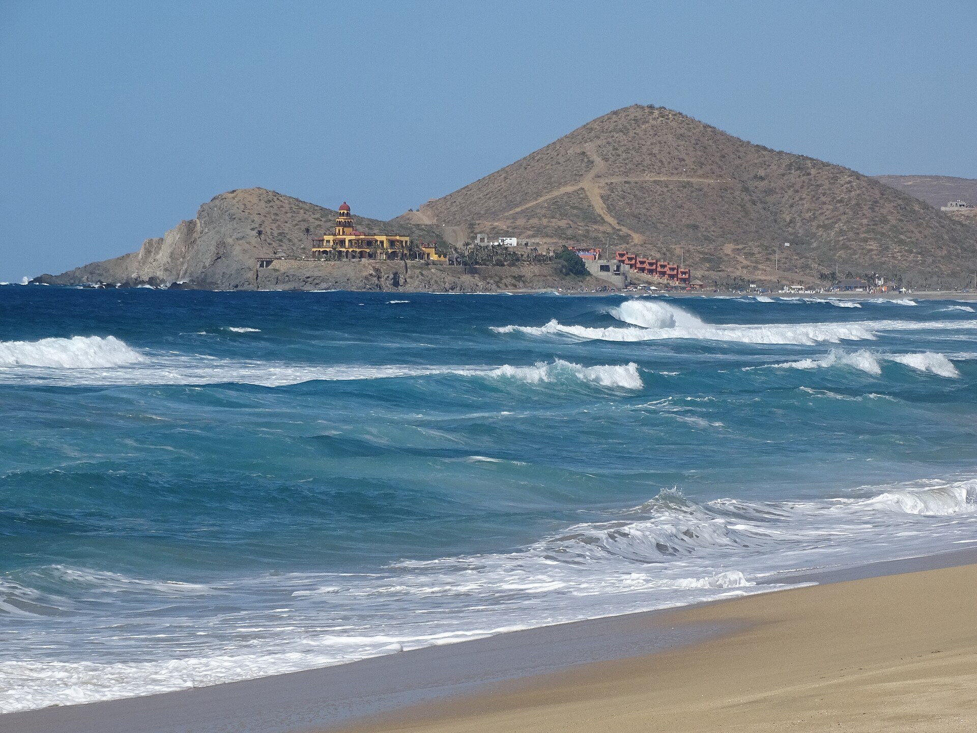 Playa Los Cerritos, cerca de Todos Santos, con oleaje azul y cerro desértico al fondo