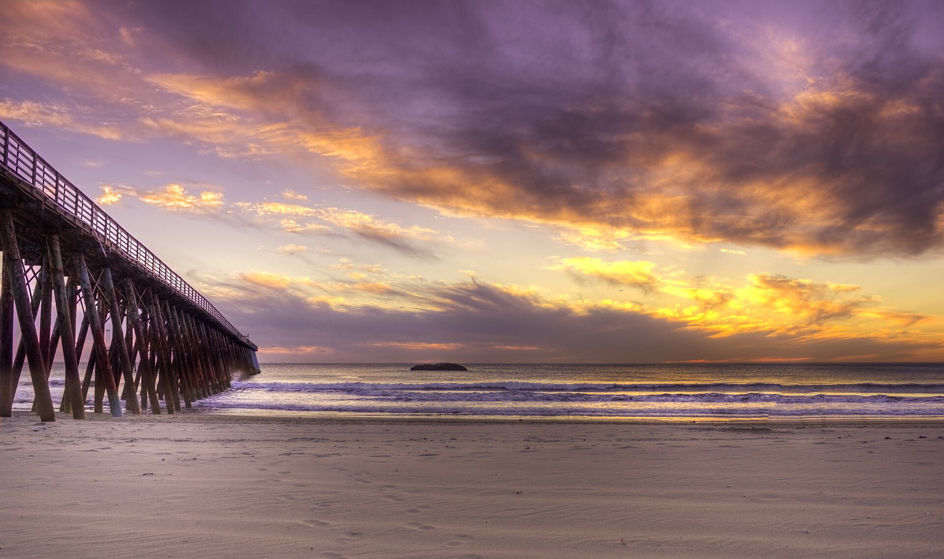 Muelle de Rosarito al atardecer con cielo dorado y morado sobre la playa del Pacífico