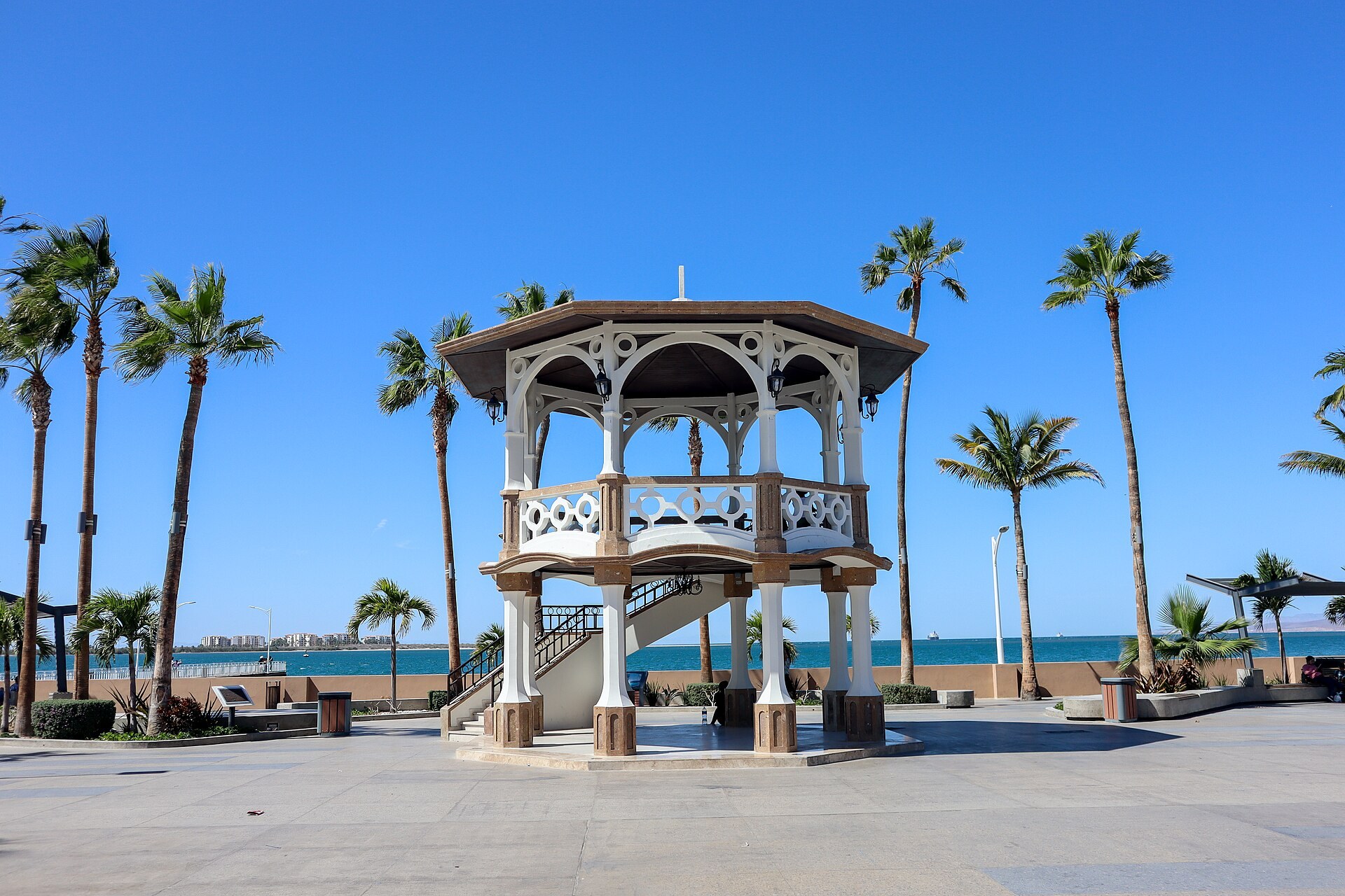 Kiosco blanco del Malecón de La Paz rodeado de palmeras con la bahía al fondo